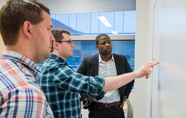 Students at a whiteboard with a faculty member